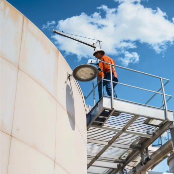 Trabalhador em uma escada inspecionando o interior de um poço de água gigante.